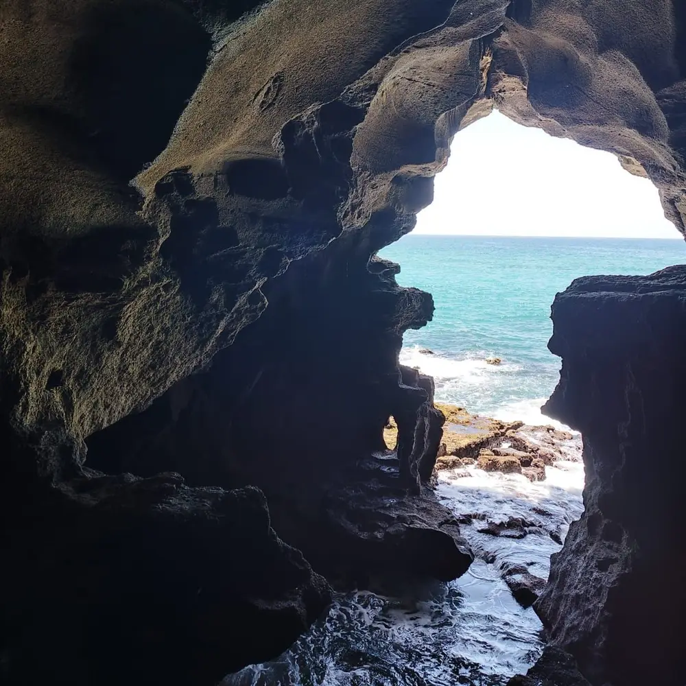 L’ouverture de la grotte d’Hercule sur l’océan, vue de l’intérieur de la grotte, avec la mer turquoise et les rochers