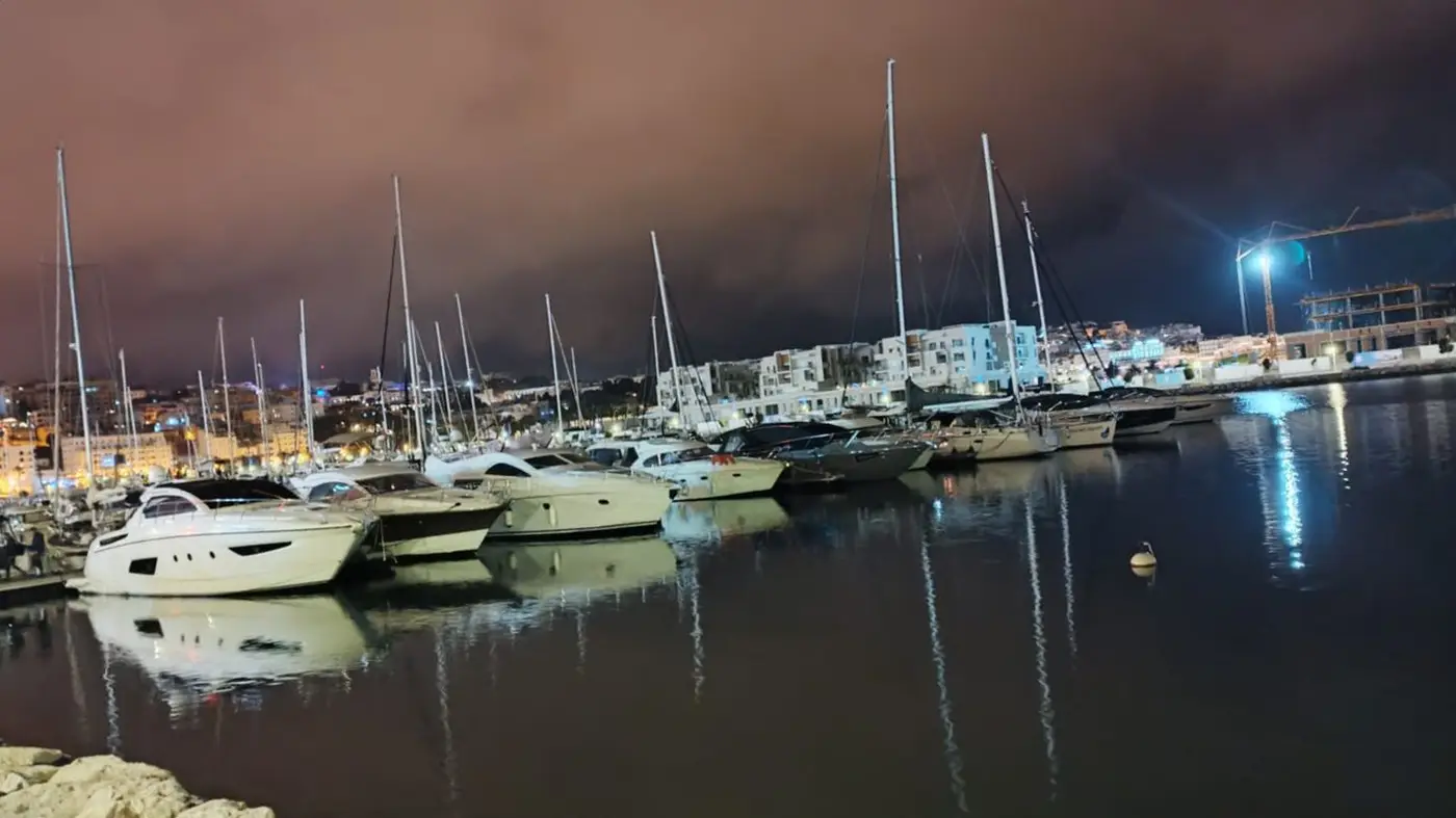 Voiliers et yachts amarrés à Tanja Marina Bay, de nuit, avec les reflets des lumières sur l’eau
