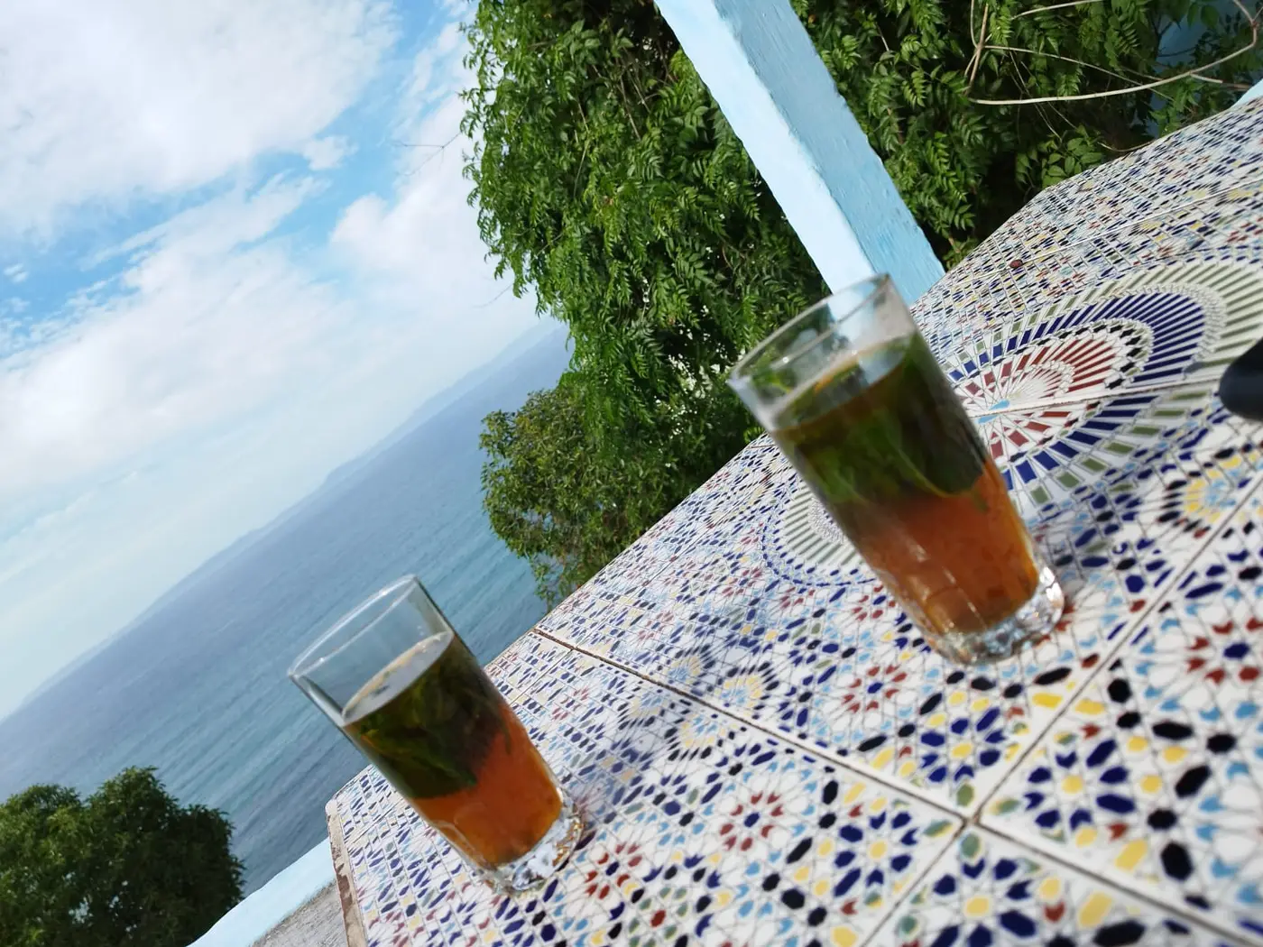 Deux verres de thé à la menthe sur une table en zellige, face à la mer et au détroit de Gibraltar